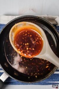 Honey sriracha in a pan with a spoon of sauce