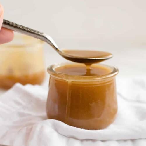 Drizzling butterscotch sauce in a spoon over a jar