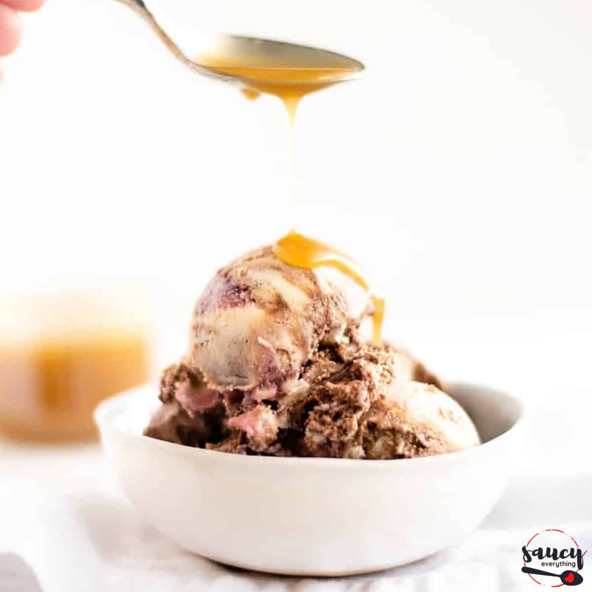 Drizzling butterscotch sauce on ice cream with a spoon