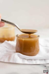 Butterscotch sauce in a spoon over a jar of sauce