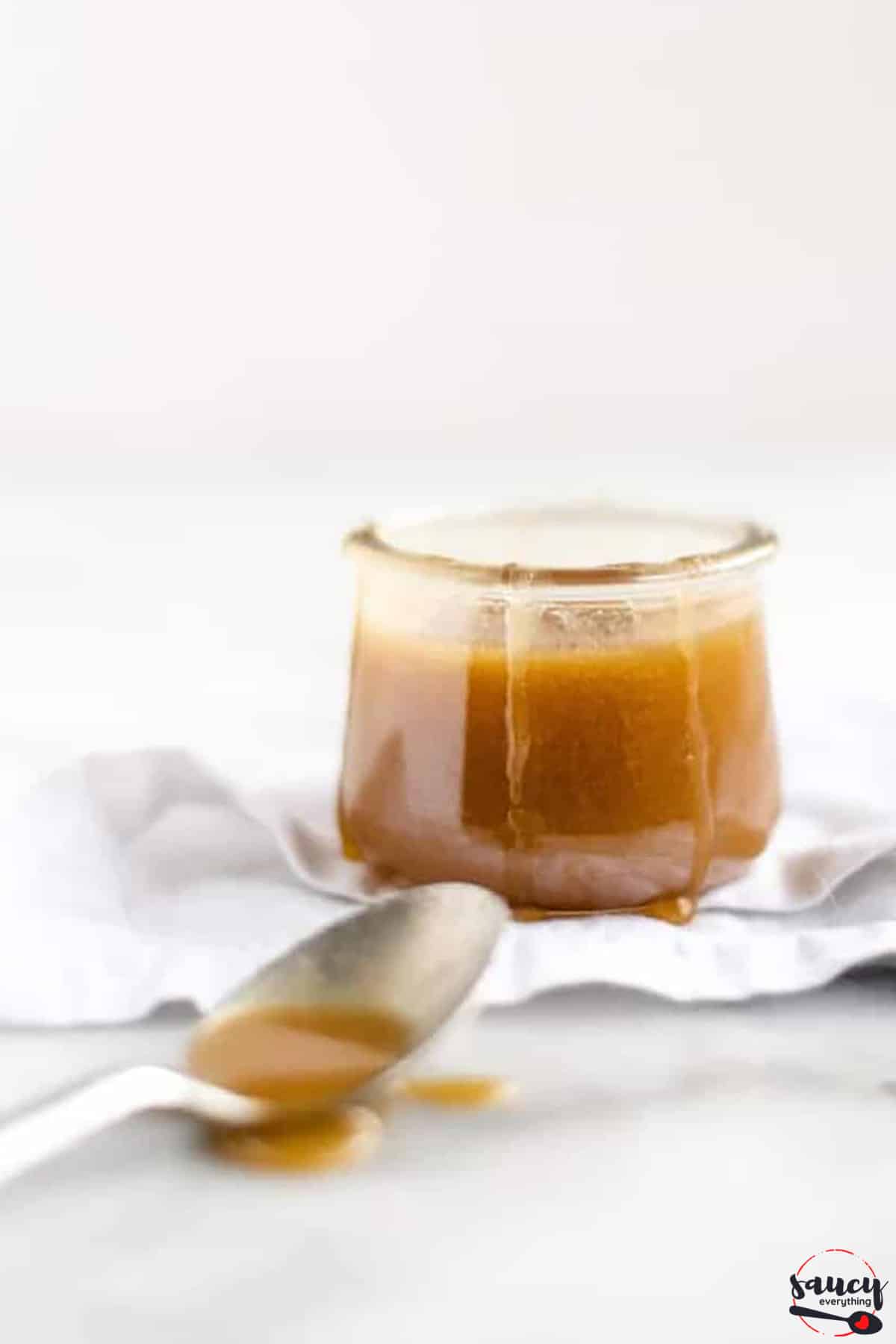 Butterscotch sauce in a jar next to a spoon