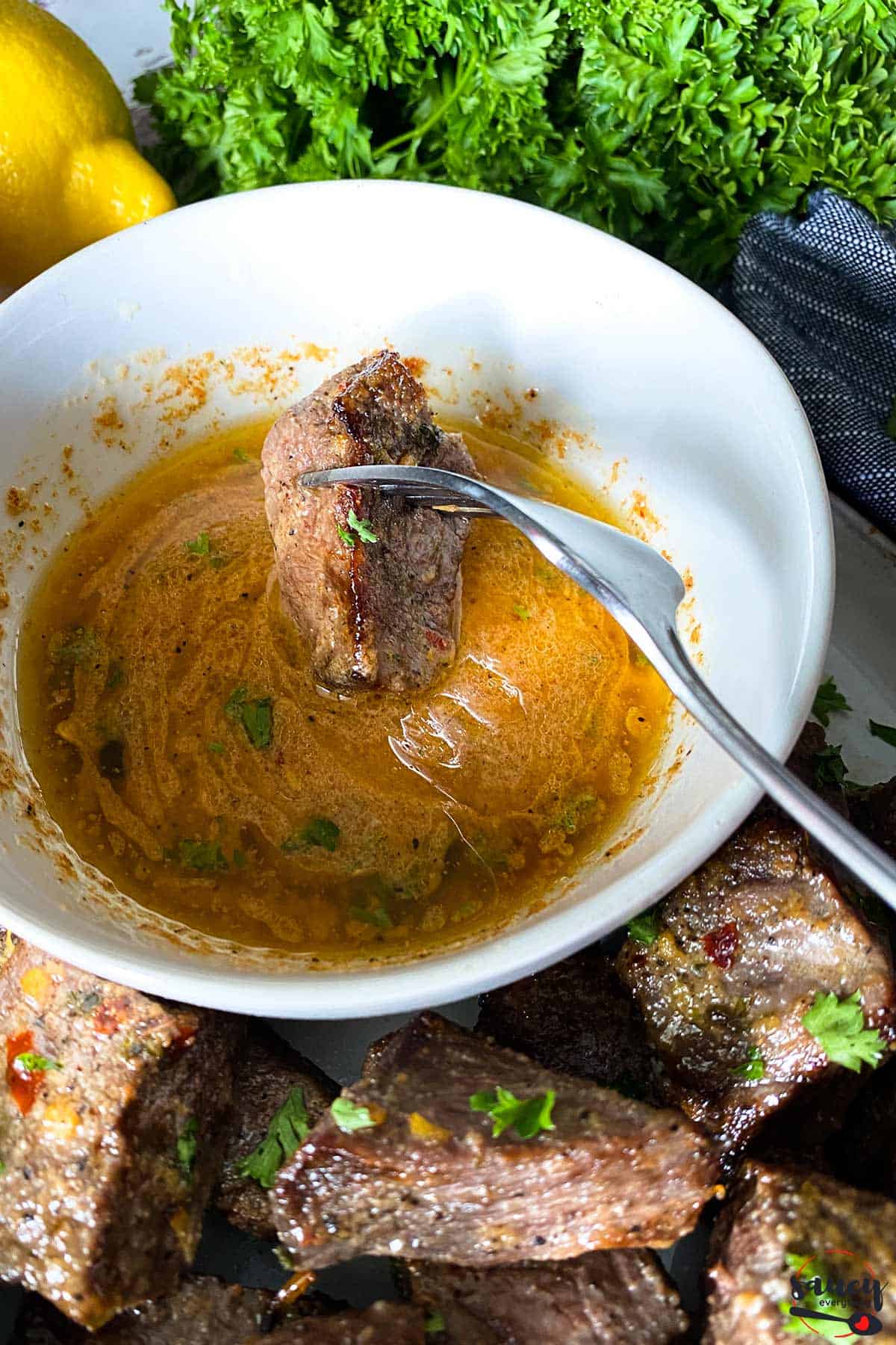Dipping a steak bite into cowboy butter sauce in a bowl