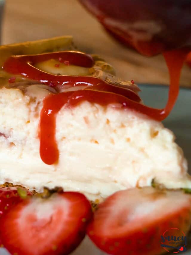 Cheesecake slice on plate with strawberry sauce drizzled on