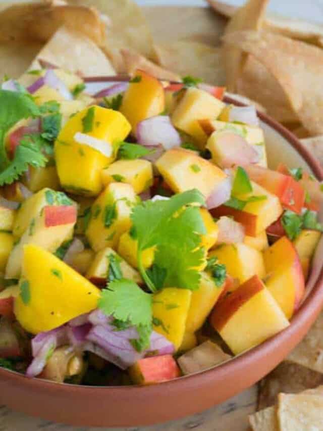 Peach and mango salsa in a bowl served with chips.