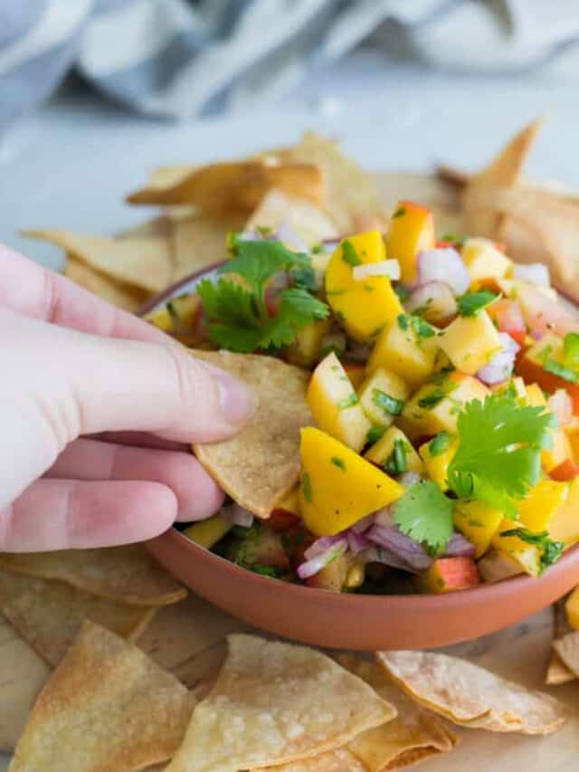Peach and mango salsa in a bowl served with chips.