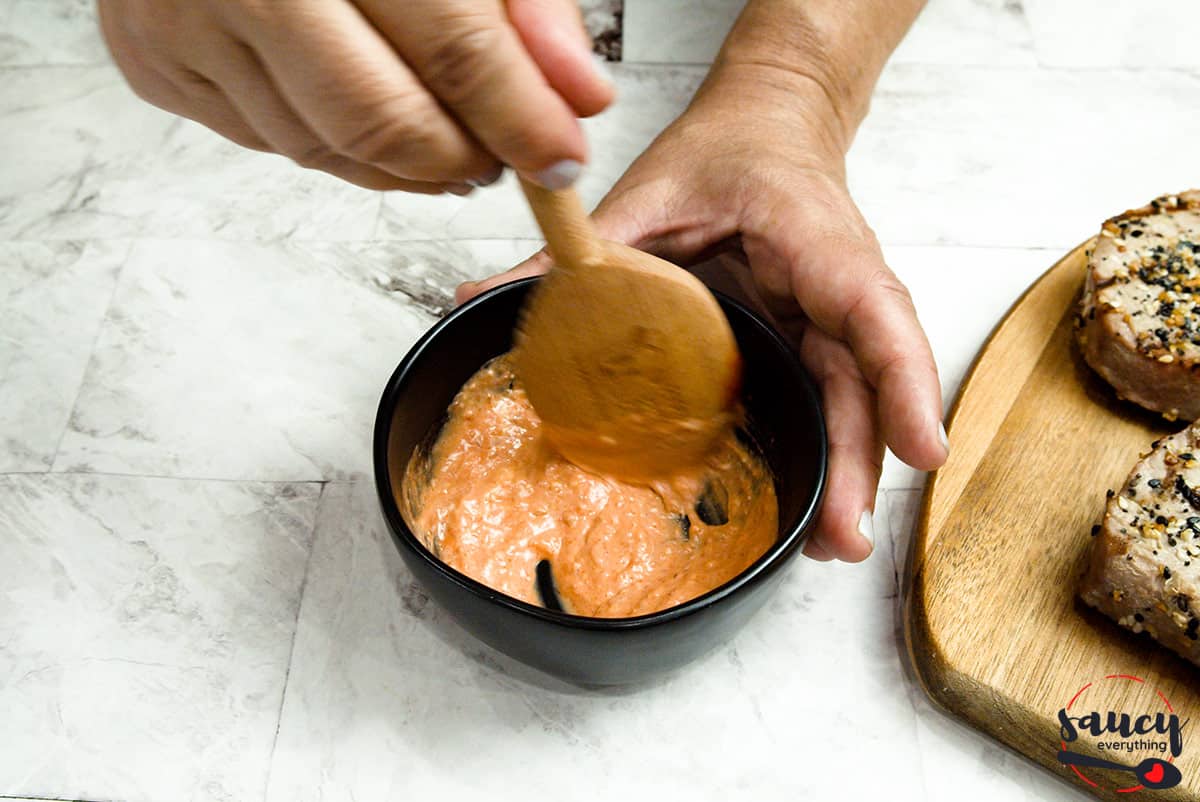 mixing spicy sriracha mayo in a bowl with a wooden spoon