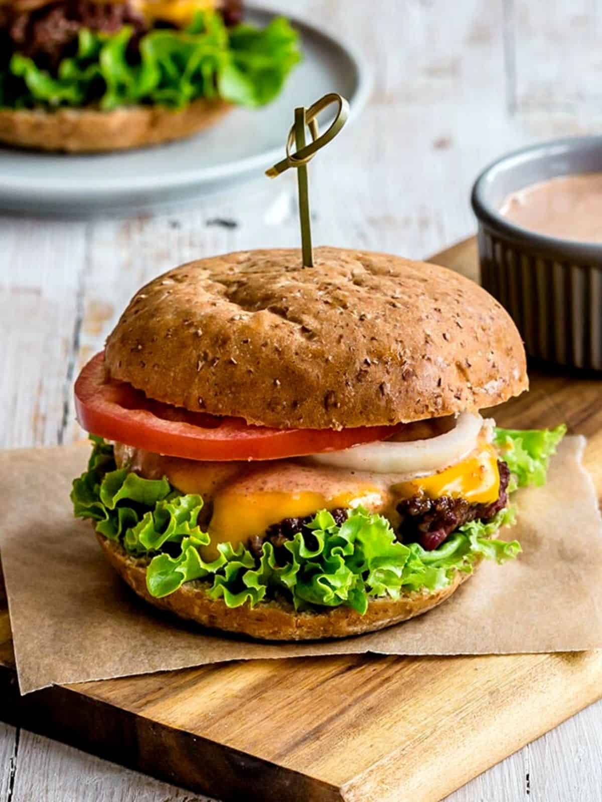 burger topped with burger sauce next to a cup of sauce
