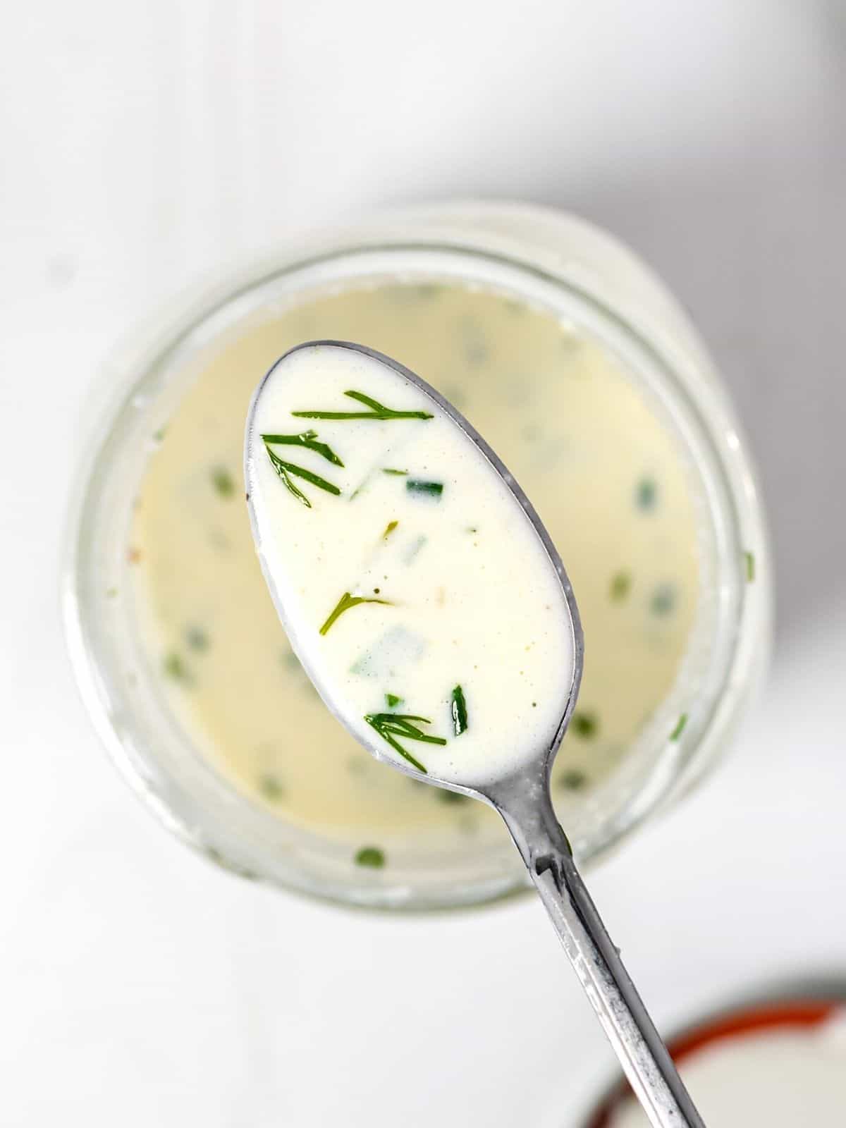 A spoonful of homemade ranch dressing over a jar of dressing