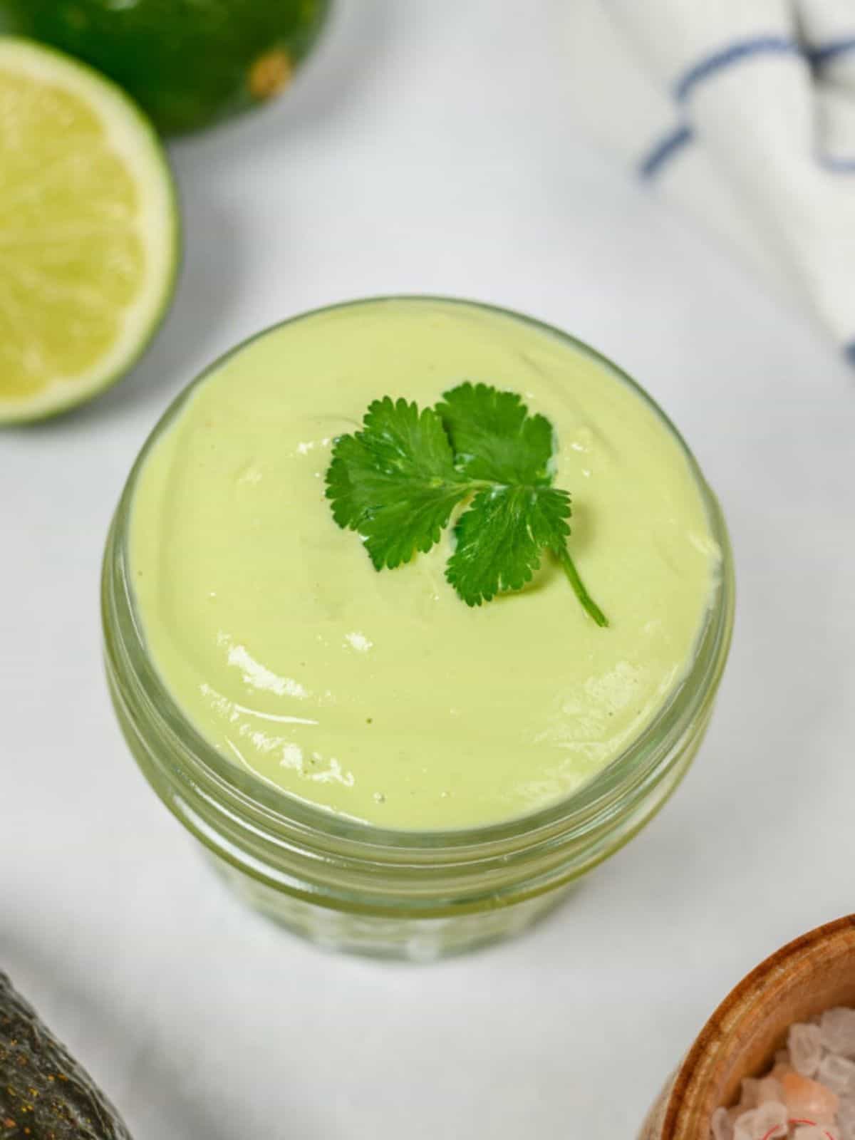 Avocado crema in a glass container with cilantro on top.