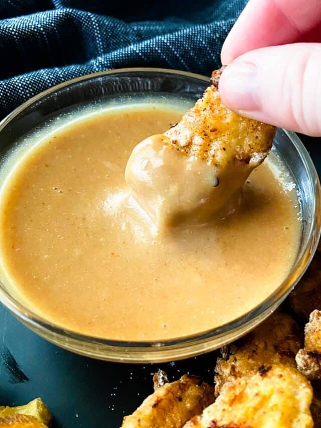 Chicken nugget being dipped into Chick-fil-A sauce.