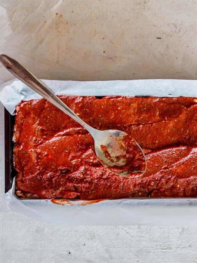 Spreading meatloaf glaze on meatloaf with a spoon
