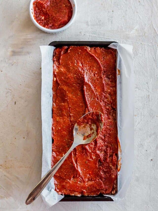 Spreading meatloaf glaze on meatloaf with a spoon