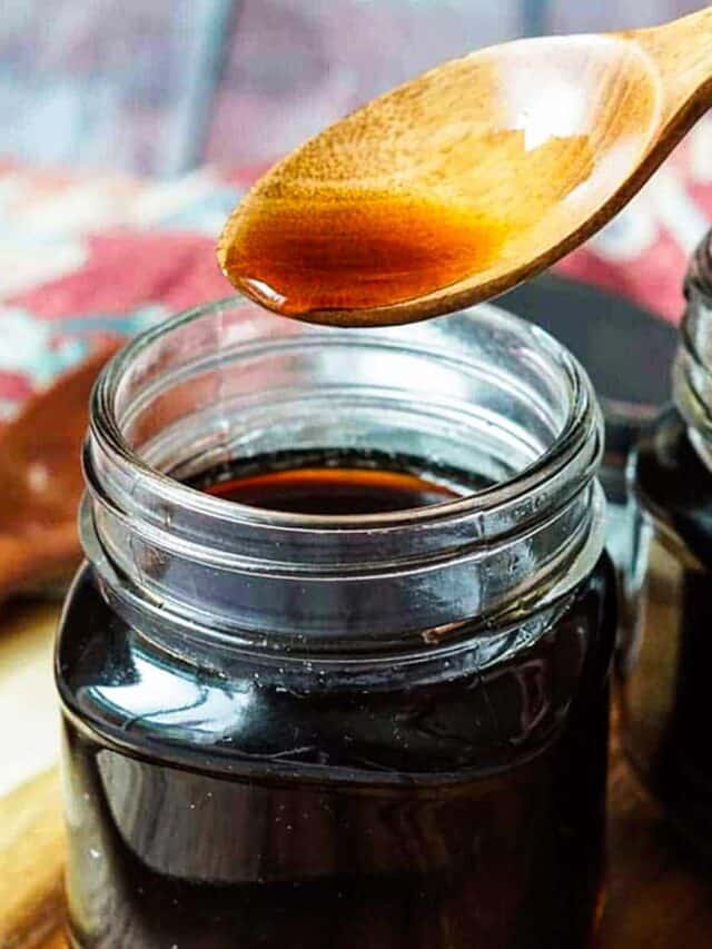 holding a wooden spoon over a jar of teriyaki sauce