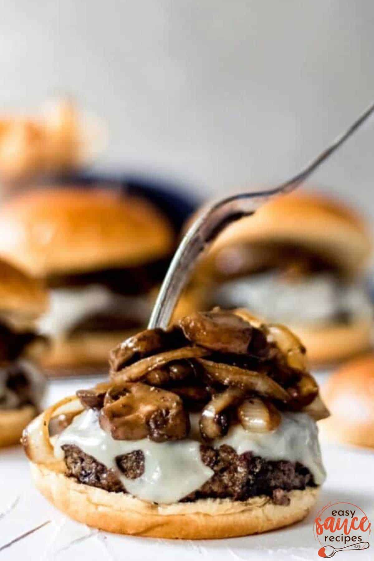 topping a burger with mushrooms and onions