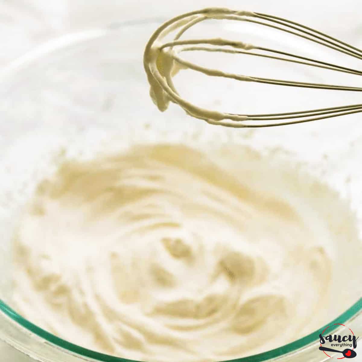 Whipped cream in a bowl with a whisk