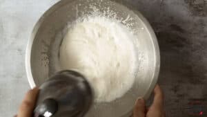 Mixing ingredients for whipped cream in metal mixer bowl