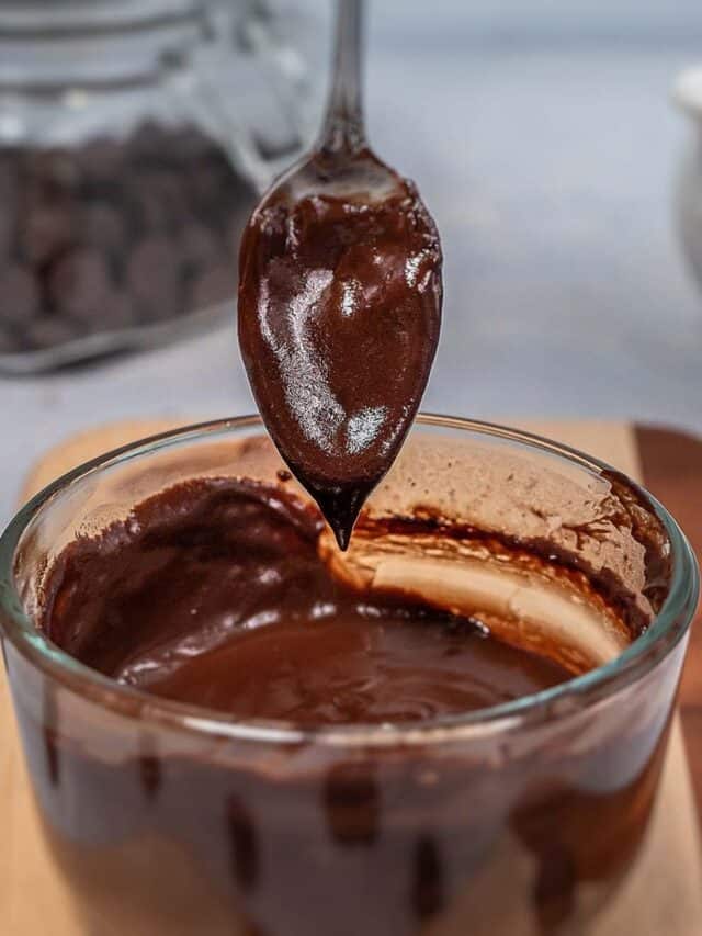 Chocolate sauce in a glass bowl with a silver spoon.