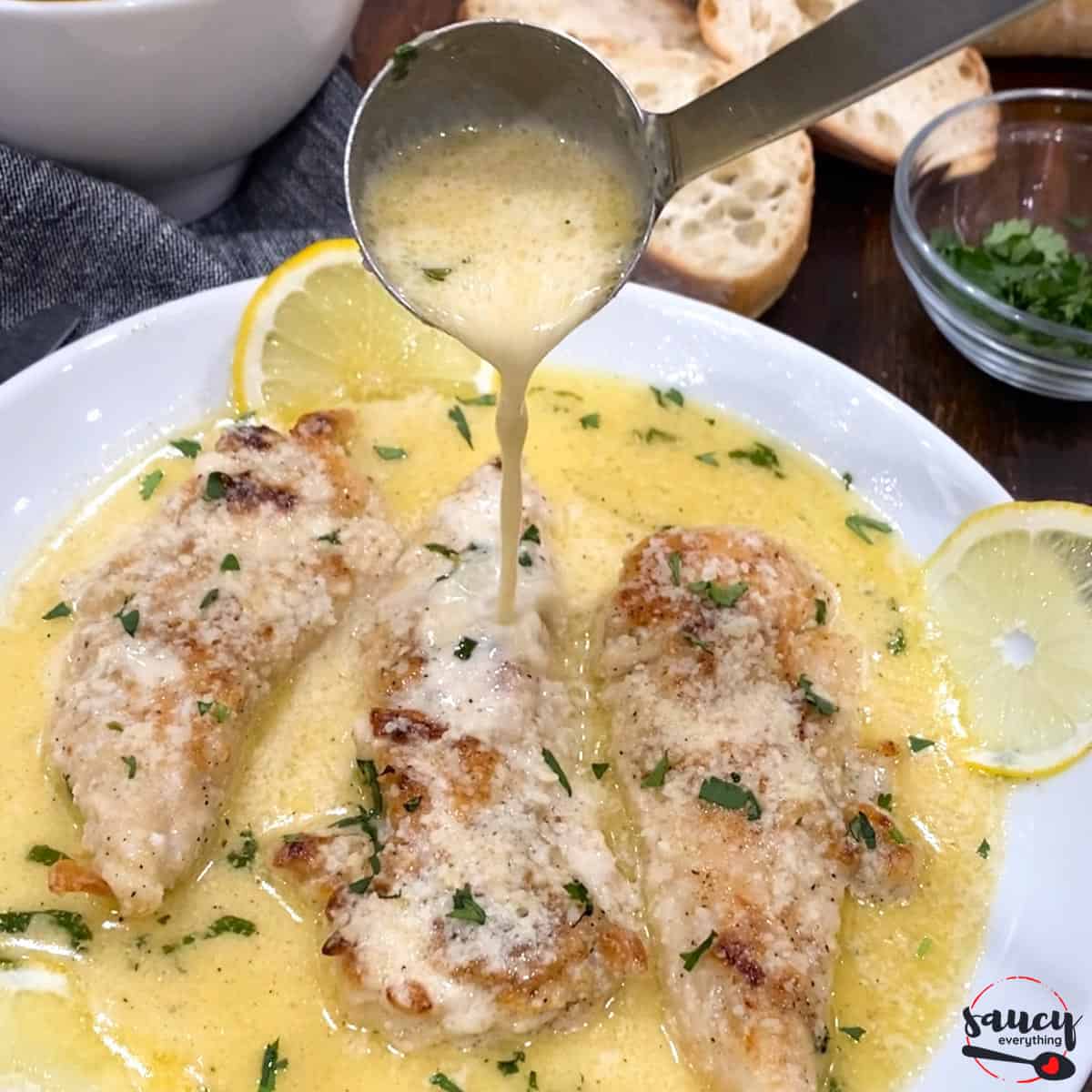 Pouring creamy lemon butter sauce over chicken cutlets on a plate