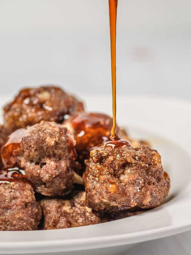 Sriracha sauce being poured over meatballs.