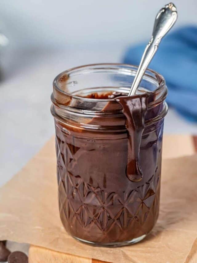 Chocolate sauce in a glass jar with a spoon.