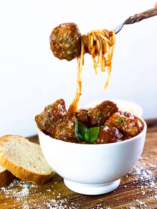 Meatball on a fork over bowl of meatballs with sauce