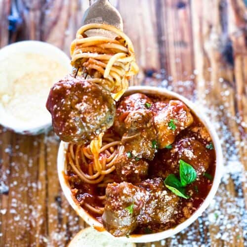 Meatball on a fork over bowl of meatballs with sauce