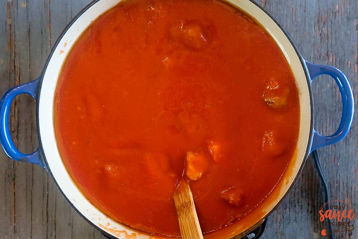 Adding tomato sauce to meat sauce in pot