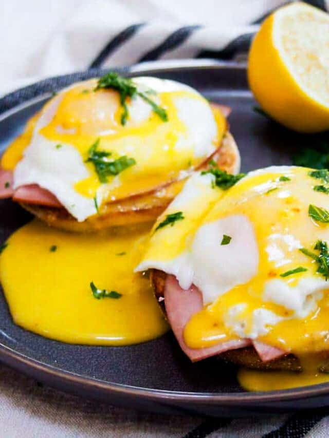 hollandaise sauce poured over eggs benedict on a black plate