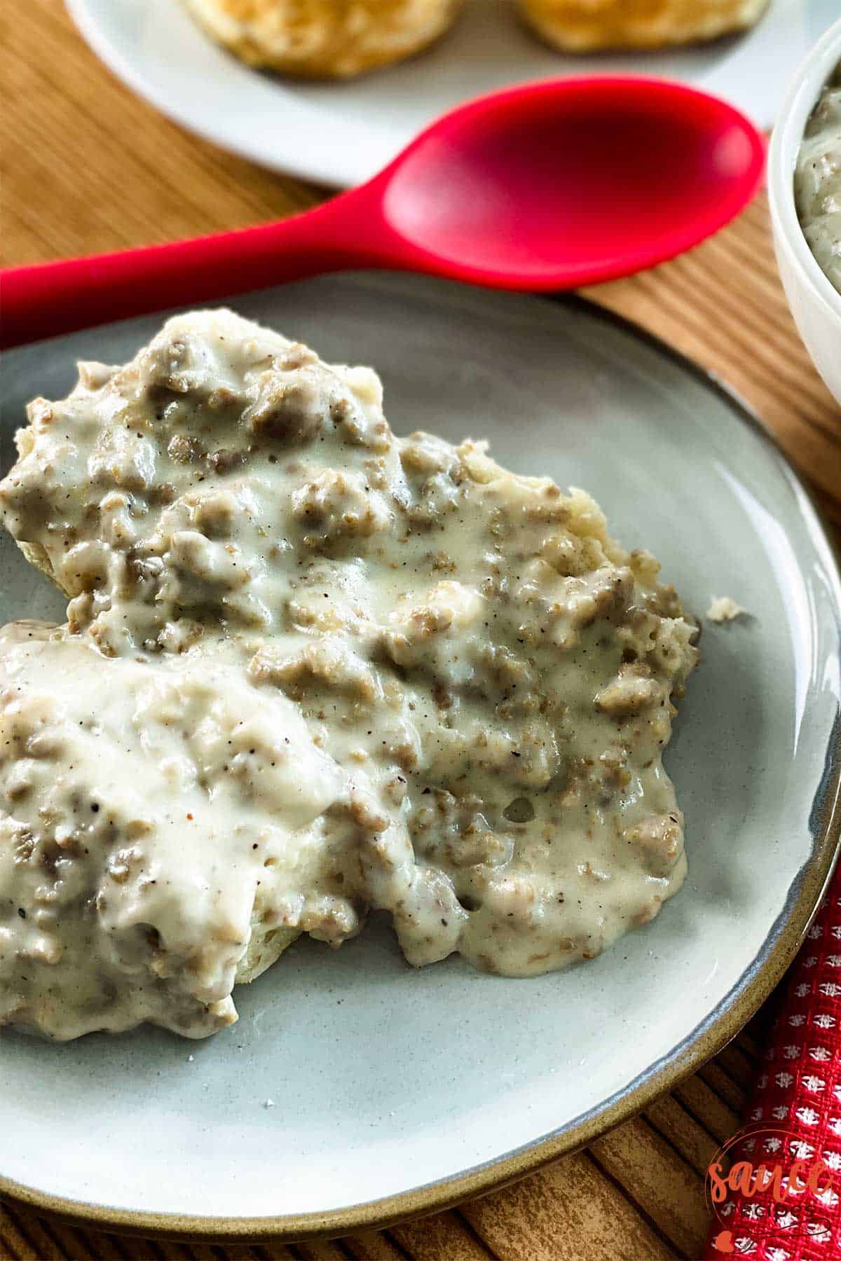 Biscuits and gravy on a plate with a red spoon