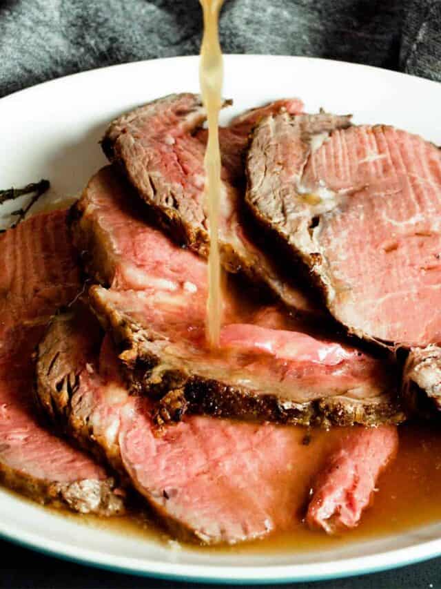 au jus being poured over sliced roast beef.