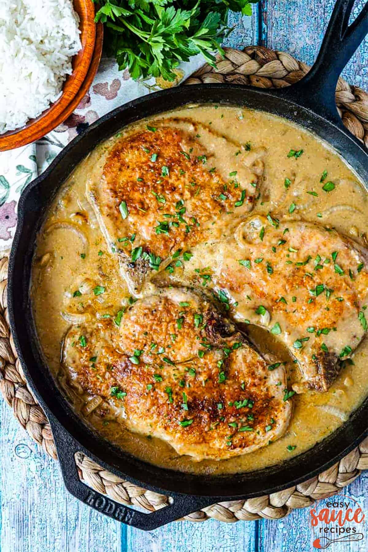 onion gravy in a skillet with pork chops next to rice