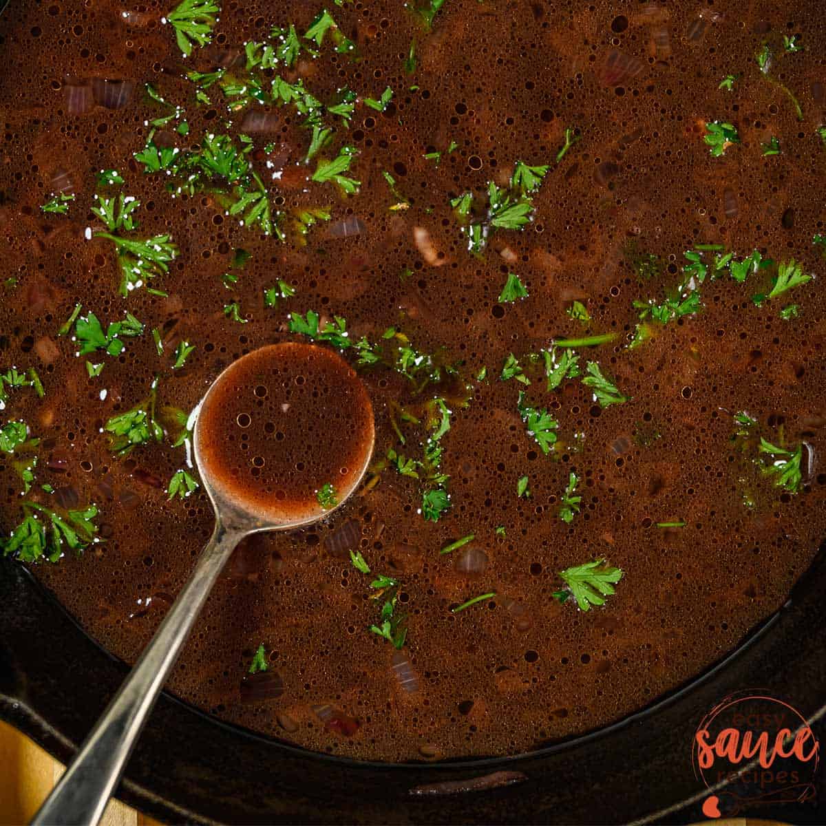 red wine sauce in a pan with a spoon and parsley