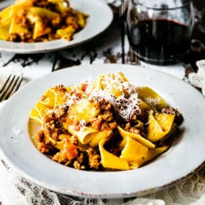 bolognese meat sauce on pappardelle pasta in a white dish
