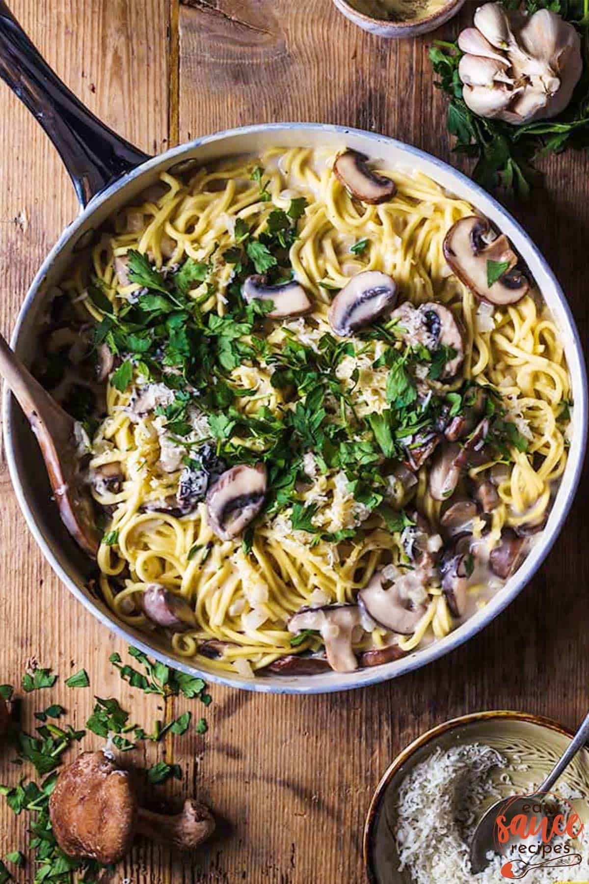 Mushroom sauce pasta in a pan with fresh herbs