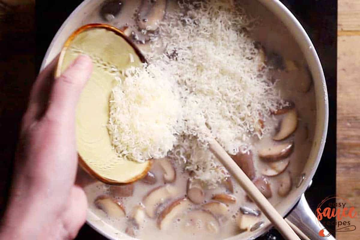 Adding parmesan to mushroom sauce in a pan
