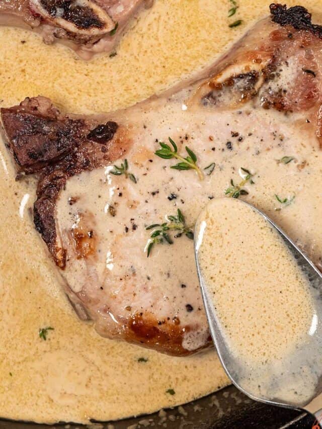 Spooning dijon mustard sauce over pork chop in a pan