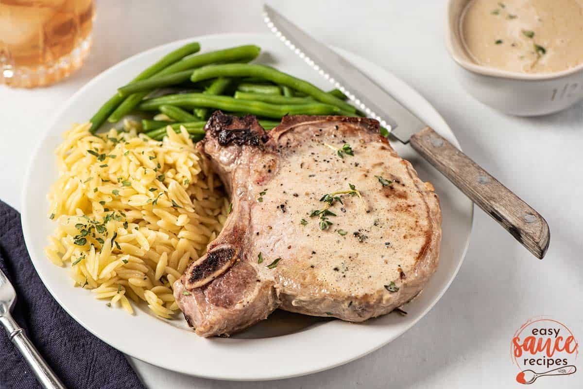 pork chops with orzo and green beans on plate with dijon mustard sauce