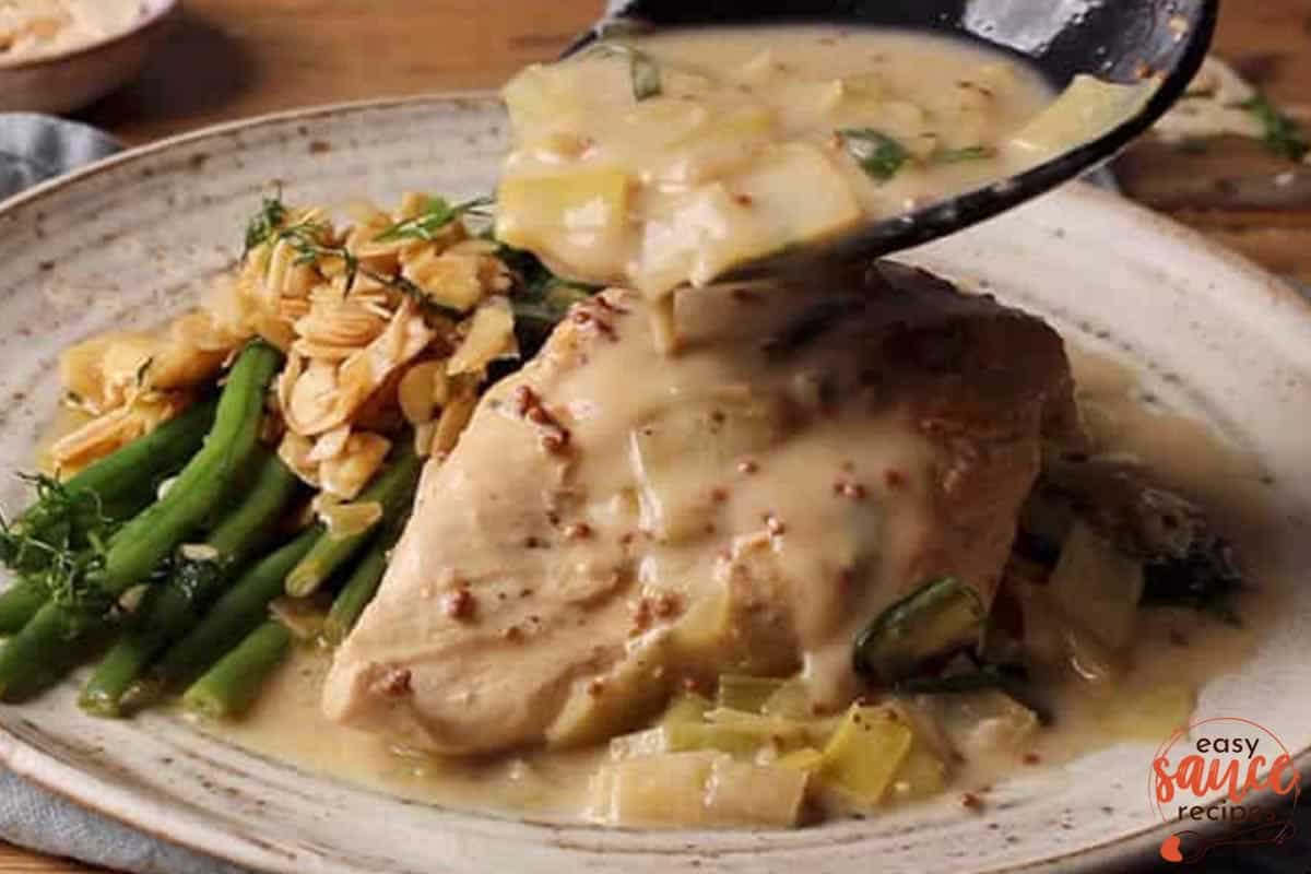 spooning leek sauce over chicken on a plate