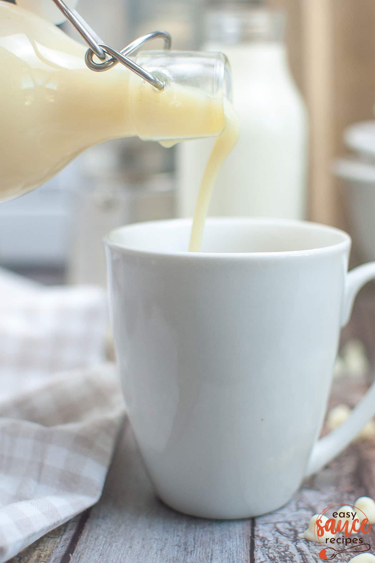 pouring white chocolate syrup in a mug