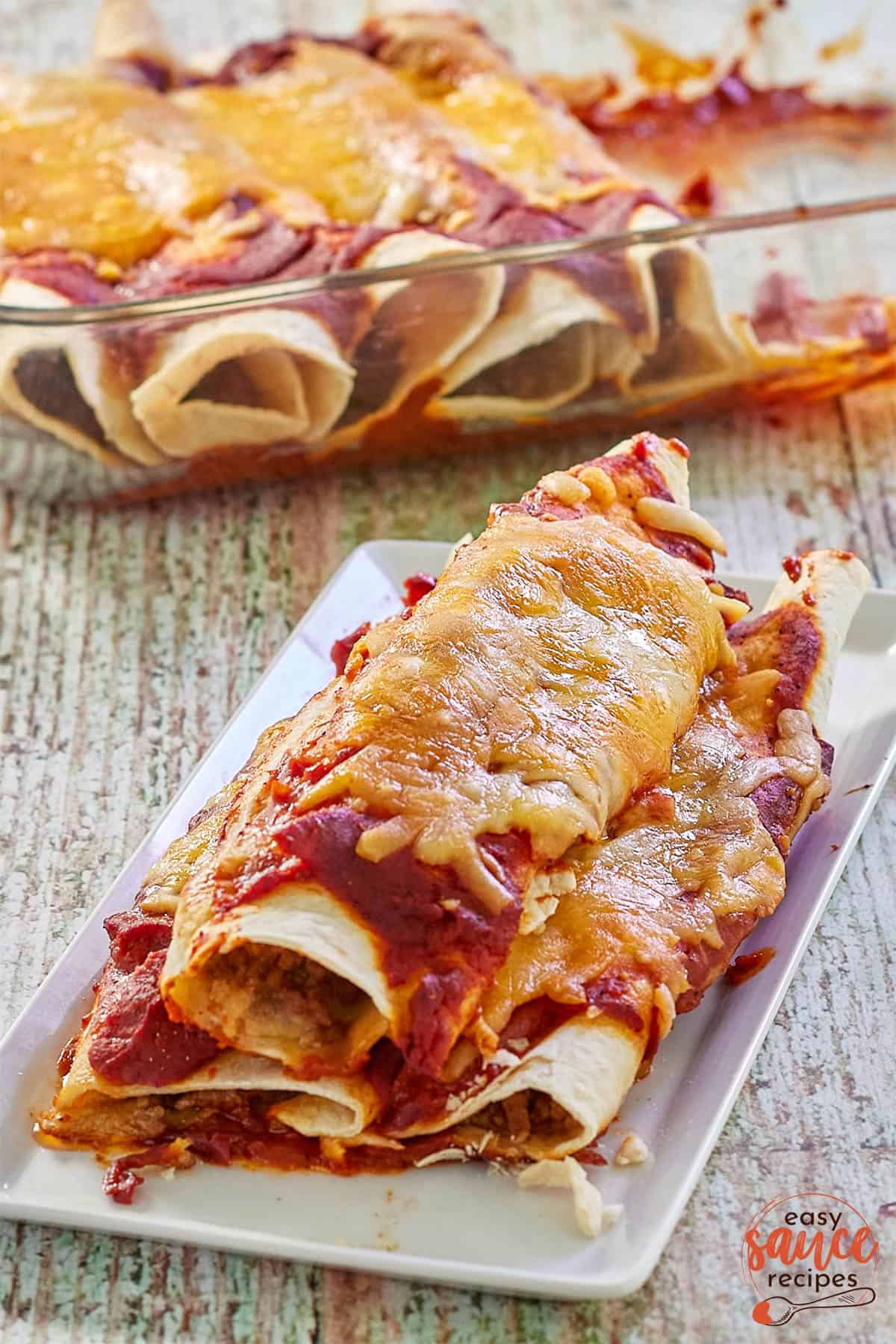baked enchiladas on a plate with red enchilada sauce
