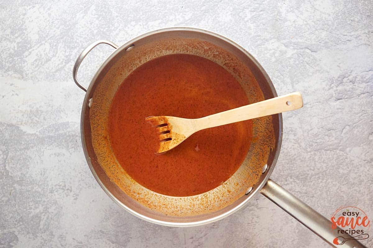 mixing enchilada sauce in a saucepan