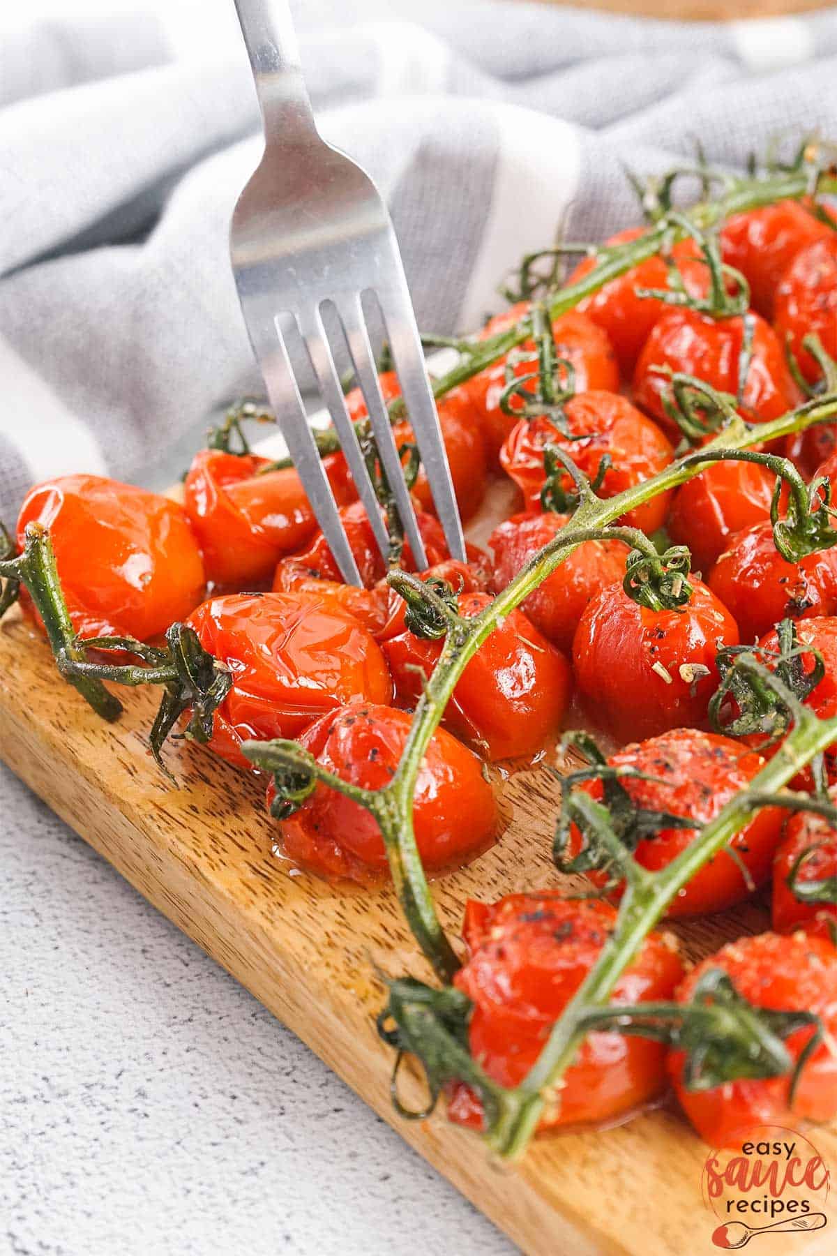 vines of roasted tomatoes on a board with a fork