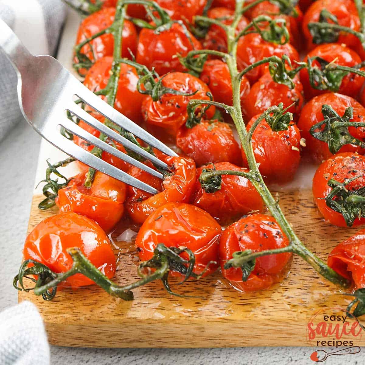 roasted tomatoes on a cutting board with a fork
