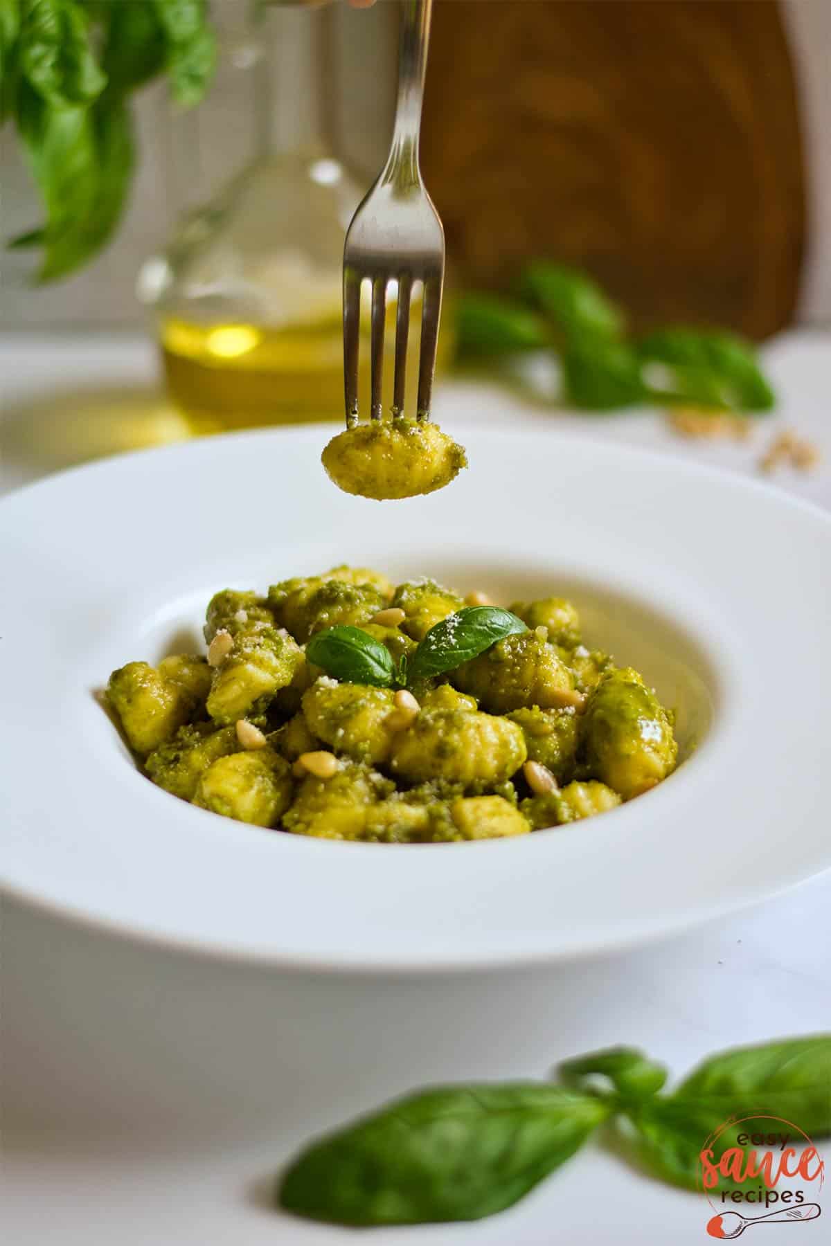 A forkful of pesto gnocchi on a white plate