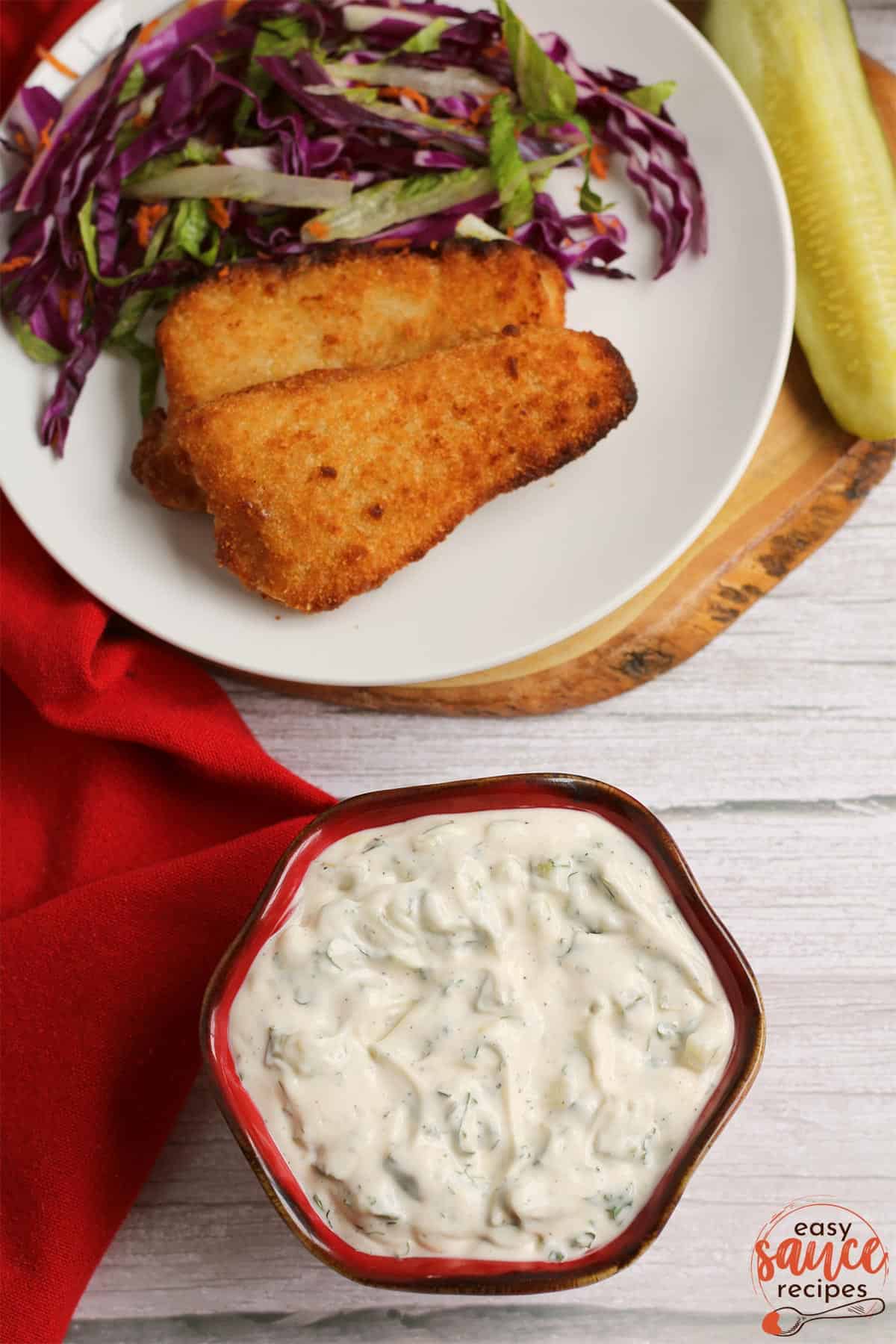 tartar sauce in a red bowl next to a plate of fried fish