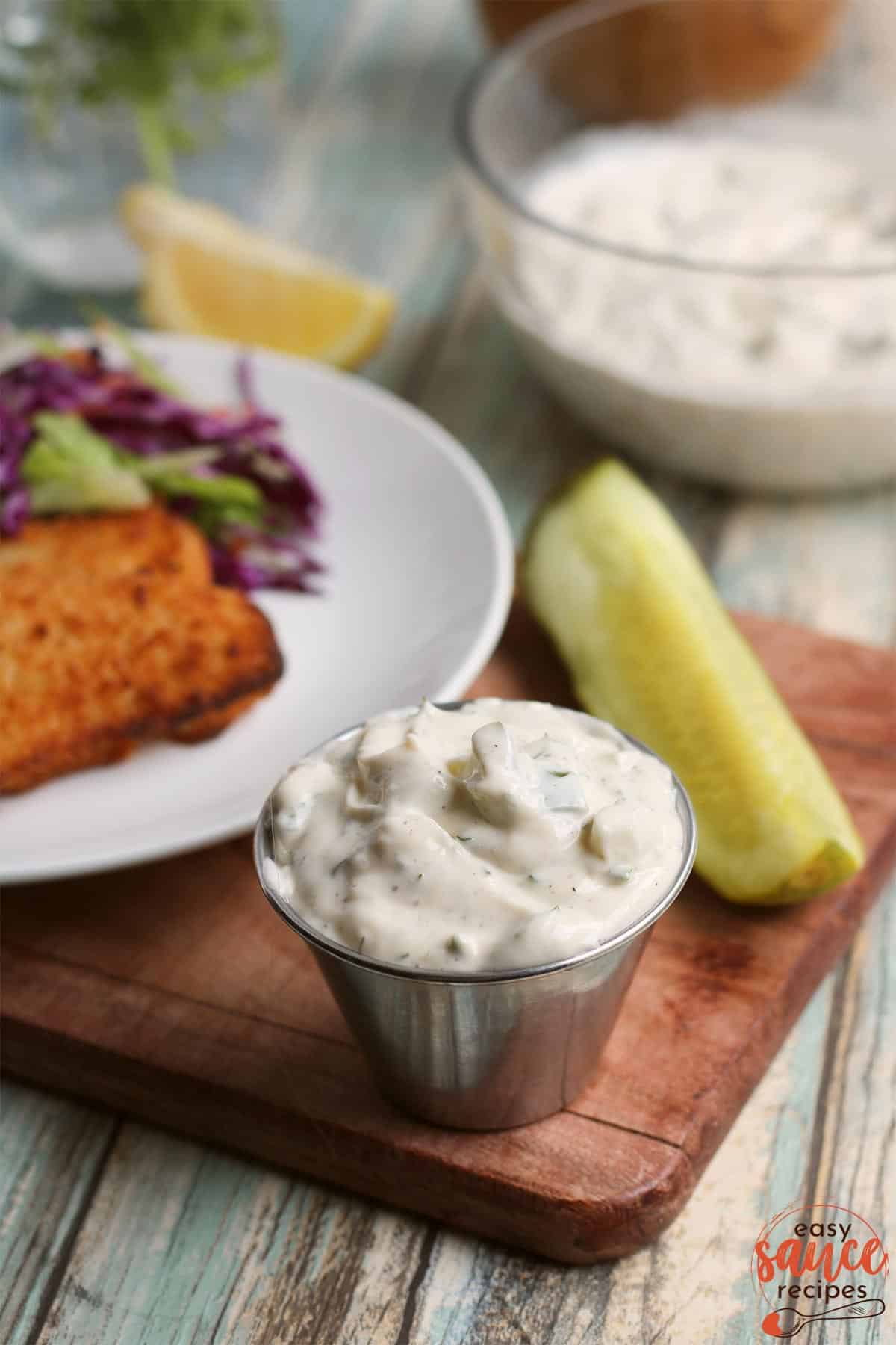 tartar sauce in a little metal bowl with a pickle and fish