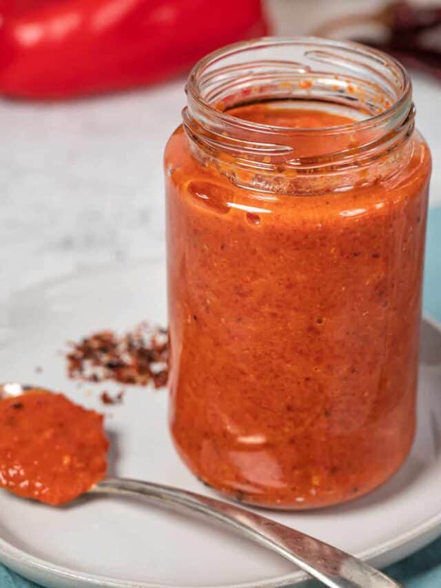 harissa sauce in a clear mason jar on a white plate with a spoon