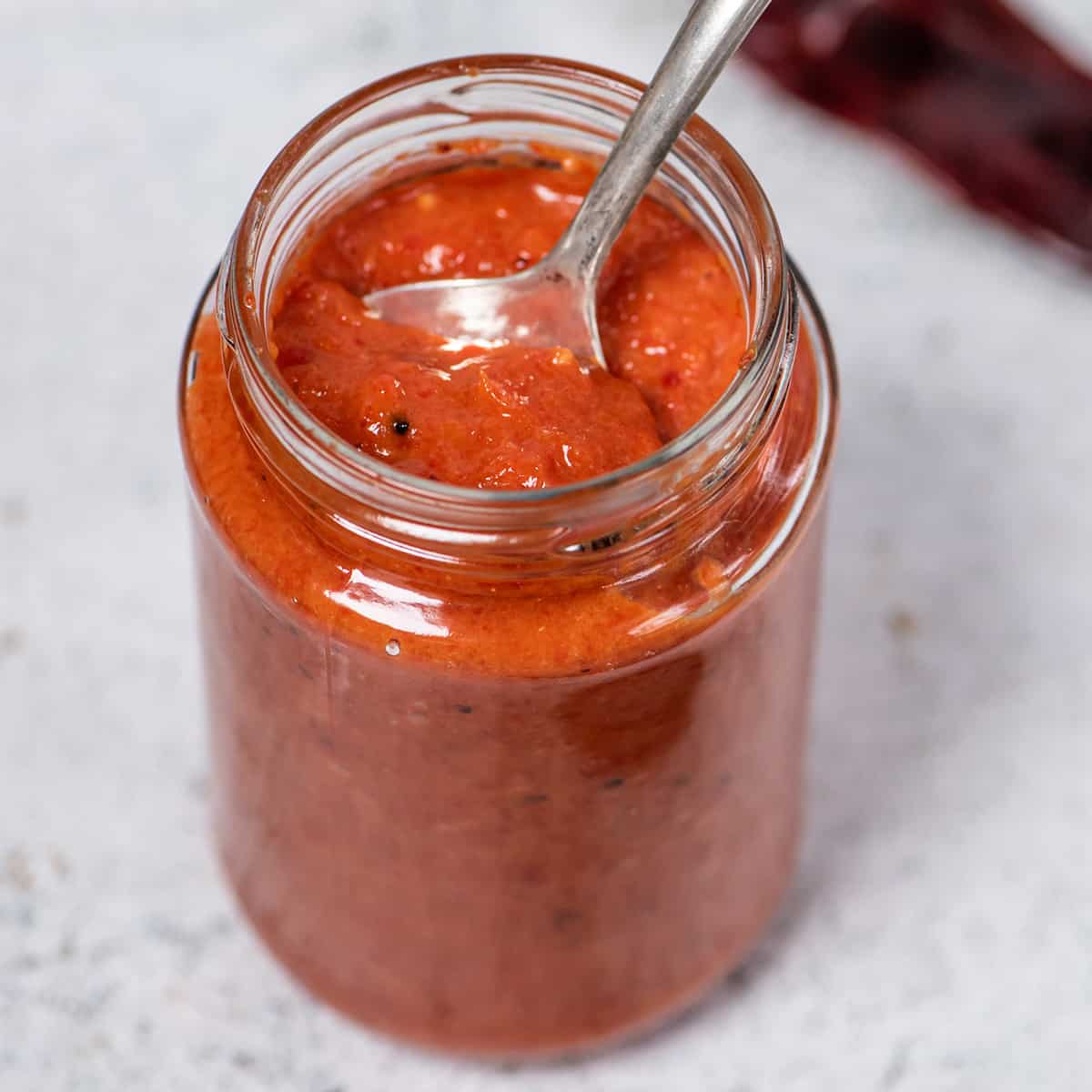 harissa sauce in a clear mason jar with a spoon inside