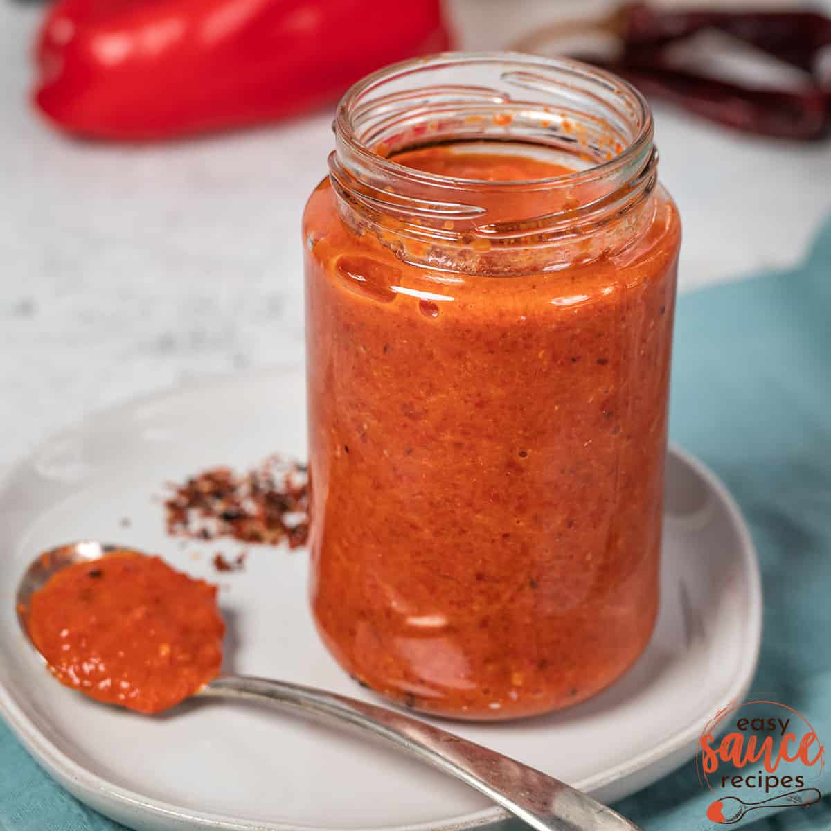 harissa sauce in a clear mason jar on a white plate with a spoon
