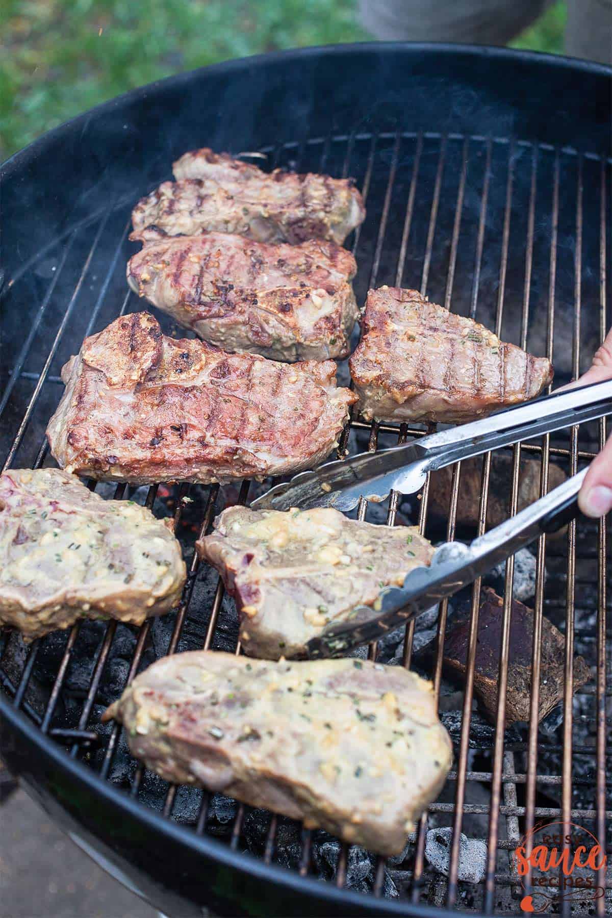 cooking lamb chops on the grill with tongs